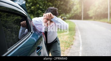 La voiture d'homme d'affaires asiatique cassée a des problèmes avec la voiture en bas pendant le travail le matin il a poussé hors de l'essence sur la route à la campagne, homme d'affaires ont t Banque D'Images