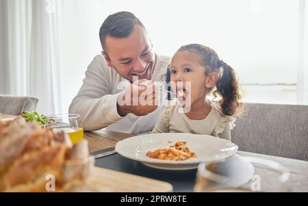 Le père nourrit la nourriture du déjeuner à la fille pour le soutien avec la santé, le développement de l'enfant et la croissance tout en se détendant à la maison. Repas, papa ou homme nourrissant enfant fille tout en étant heureux et profiter de la qualité du temps ensemble Banque D'Images