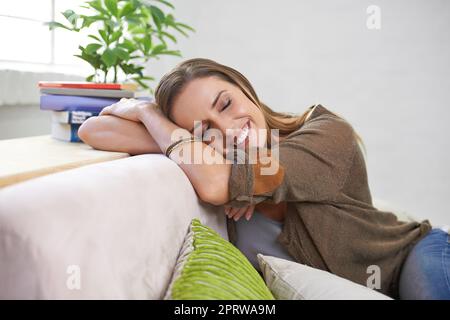 Elle s'est endormie sur le canapé. Une femme attrayante se détendant sur le canapé à la maison. Banque D'Images