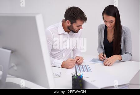 Obtenir l'approbation du patron. Deux jeunes collègues discutent de documents au bureau Banque D'Images