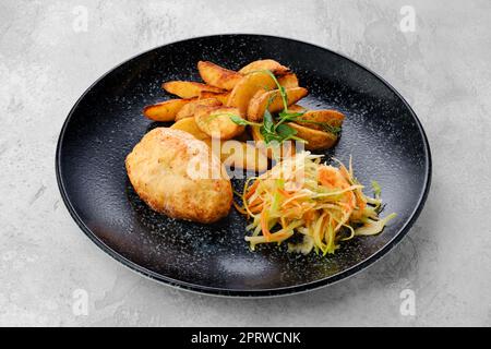 Côtelette de Kiev farcie de fromage et de beurre, servie avec des quartiers de pommes de terre et de la choucroute Banque D'Images