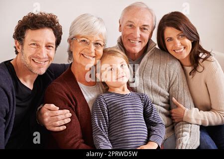 Bénis de s'avoir les uns les autres. Portrait court d'une famille de plusieurs générations heureuse assise ensemble sur un canapé Banque D'Images