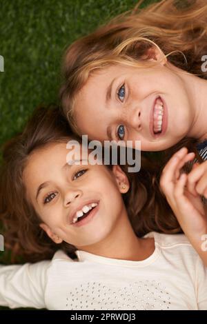 Amis pour toujours. Deux petites filles couchés sur le dos à l'extérieur. Banque D'Images