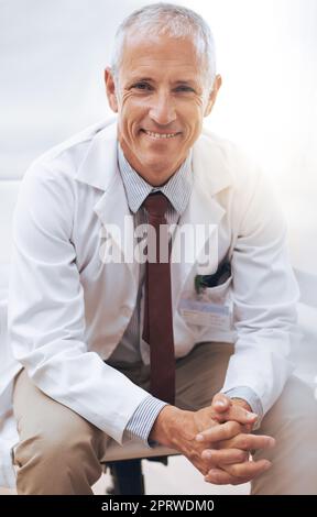 Votre santé est ma priorité numéro un. Portrait d'un homme souriant médecin assis dans son bureau Banque D'Images