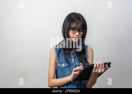 Femme asiatique portant des lunettes tenant une tablette sur l'arrière-plan.technologie d'apprentissage en ligne concept d'éducation. Banque D'Images