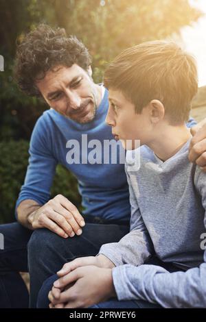 Donner à son fils des conseils paternels. Un père et un fils ayant un cœur à cœur dans la cour Banque D'Images