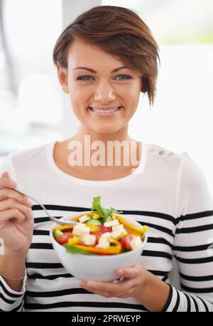 J'ai hâte de ma salade. Portrait d'une jeune femme gaie qui mange de la salade. Banque D'Images