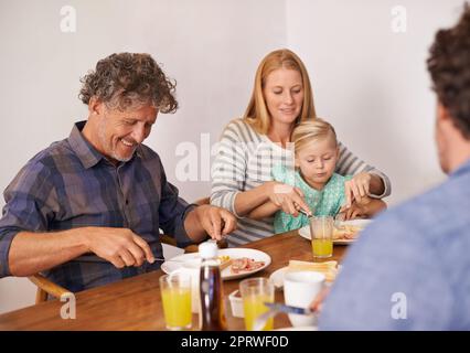 Le chemin vers le cœur des grands-pas a toujours été par son ventre. Une photo courte d'une famille de plusieurs générations qui prend le petit déjeuner à la maison. Banque D'Images