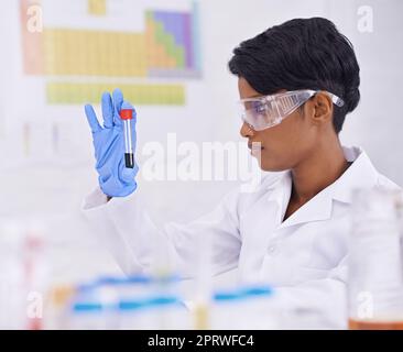 Conserver le produit fini tant attendu. Vue latérale d'un beau jeune scientifique examinant un tube à essai dans son laboratoire. Banque D'Images