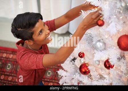 Sa partie préférée de Noël. Un gros plan d'une belle jeune femme décorant son arbre de Noël. Banque D'Images