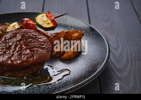 Vue en gros plan du steak de bœuf avec des quartiers de pommes de terre et des légumes grillés Banque D'Images