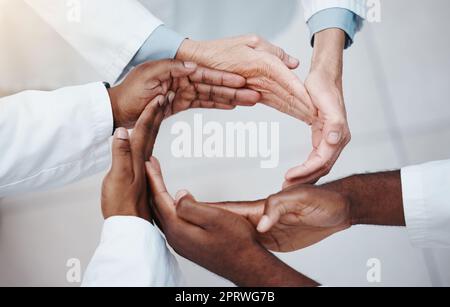 Les soins de santé, le travail d'équipe et les médecins font la main dans un cercle de soutien, de confiance et de diversité. Connexion, collaboration et partenariat en médecine. Succès, espoir et unité, groupe de travailleurs médicaux ensemble. Banque D'Images