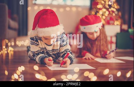 Les enfants sont à l'intérieur et écrivent des lettres pour le Père Noël. Banque D'Images