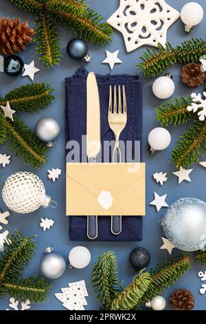 Table de Noël bleue et blanche avec enveloppe près des décorations et branches de sapin vue du dessus Banque D'Images