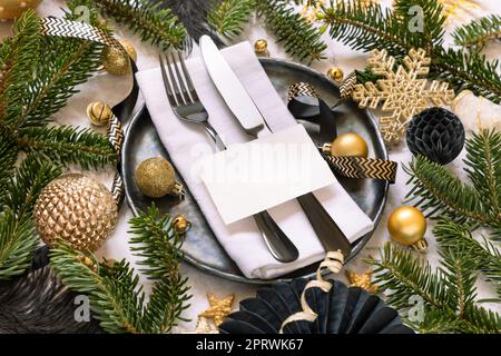 Table de Noël noire et dorée avec carte de placement, ornements et branches de sapin. Maquette Banque D'Images
