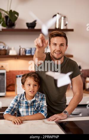 Voyons à quel point nos avions peuvent aller, un homme et son jeune fils jouant avec des avions en papier à la maison. Banque D'Images
