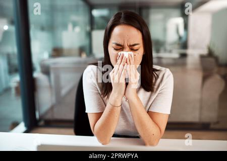 Il fait face à un nez bouché et qui coule. Une jeune femme d'affaires soufflait le nez tout en travaillant dans un bureau. Banque D'Images