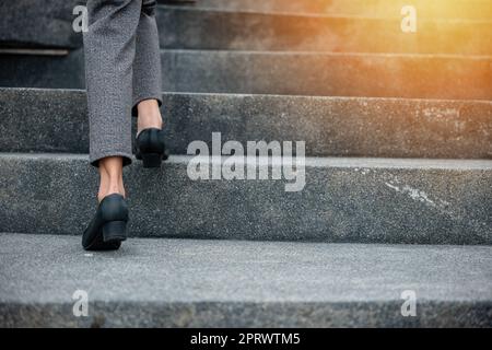 Gros plan les jambes d'une femme d'affaires se précipitent sur l'escalier Banque D'Images