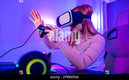 Joueur en VR casque lunettes explorant métaverse joue en ligne jeu vidéo touchant quelque chose sur l'air et de maintenir le joystick Banque D'Images