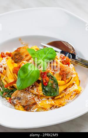 tagliatelle aux pâtes avec sauce tomate, chammignon et feuilles de basilic Banque D'Images