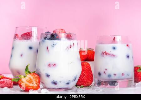 Cocktail de fruits de lait d'été sans alcool, lait de noix de coco végétalien doux sans lait de vache, avec fraise fraîche, myrtille, framboise et glace pilée, sur b Banque D'Images