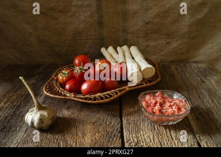 Tomates et racine de raifort pour faire un assaisonnement épicé. Légumes mûrs sur fond sombre Banque D'Images