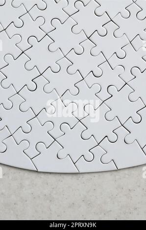 Un puzzle blanc de forme complète repose sur une surface en pierre traitée. Image texturée avec espace de copie