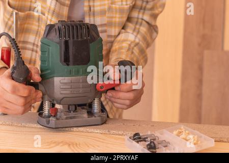 Grand angle de travail de récolte utilisant la machine de routeur électrique tout en travaillant avec le bois dans l'atelier de menuiserie Banque D'Images