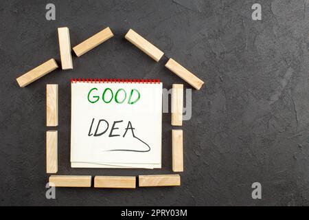 vue de dessus maison en forme de blocs de bois bonne idée écrit sur le bloc-notes sur table noire Banque D'Images