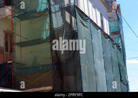 Restauration du bâtiment. Échafaudage et treillis de protection vert pour bâtiment. Techniques de sécurité pendant les travaux de construction. Banque D'Images