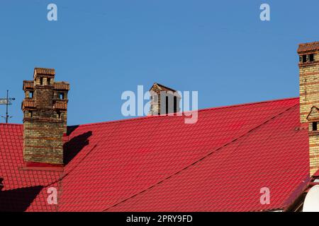 cheminée en brique rouge en haut de la maison du village. Un toit en tuiles sur le fond du ciel. Banque D'Images