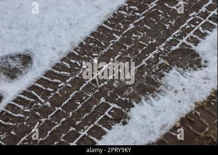 Pistes de voiture sur une route enneigée. Route glissante, danger, risque de dérapage. Traces de traces de pneus d'hiver. Banque D'Images