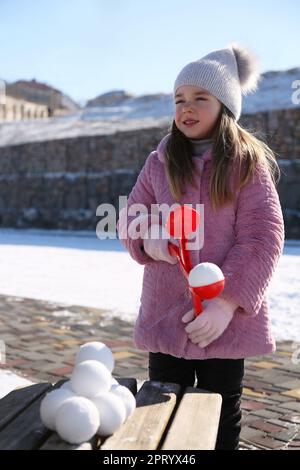 Adorable petite fille jouant avec le snowball Maker à l'extérieur Banque D'Images