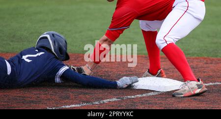 Le joueur qui couvre la base de thrid en marquant le coureur qui glisse dans la base pendant un match de baseball d'école secondaire. Banque D'Images