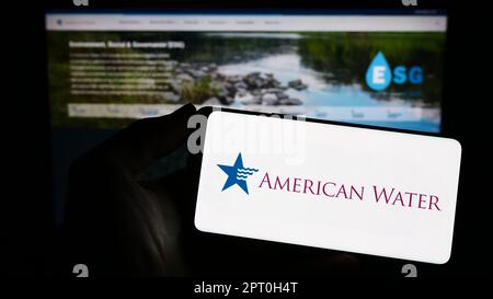 Personne tenant un smartphone avec le logo d'American Water Works Company Inc. À l'écran devant le site Web. Mise au point sur l'affichage du téléphone. Banque D'Images