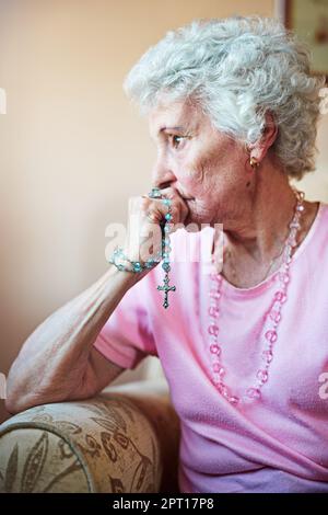 La prière lui donne l'espoir en temps de désespoir. Plan court une femme âgée tenant un rosaire dans la prière Banque D'Images