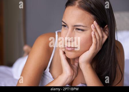 Une jeune femme qui s'est allongée sur son lit a l'air attentionnés Banque D'Images