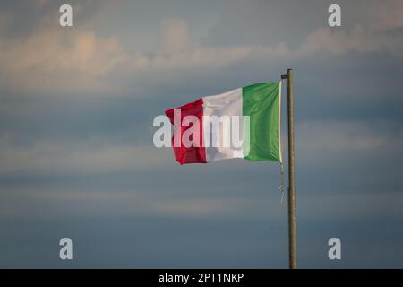 Grand drapeau italien agitant dans le vent au lever du soleil Banque D'Images