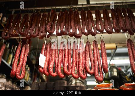 Marché des bouchers. saucisses séchées accrochées à des crochets dans une cabine du marché Banque D'Images