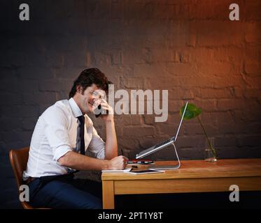 Bien sûr, nous pouvons le faire pour vous. un homme d'affaires parlant au téléphone tout en travaillant tard au bureau Banque D'Images