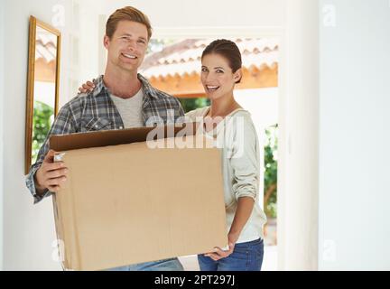 Entrer dans notre nouvelle vie ensemble. un jeune couple portant une boîte dans sa nouvelle maison Banque D'Images