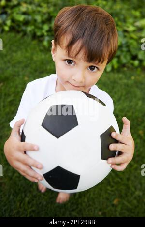 Football d'arrière-cour. Un petit garçon sucré avec une balle de football dans l'arrière-cour Banque D'Images