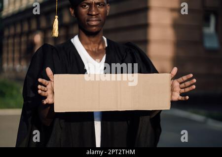 Portrait gros plan de chômeurs noir gars debout avec une affiche en carton sur la rue à la recherche d'un travail, espace de copie libre. Diplôme universitaire ou collégial Banque D'Images