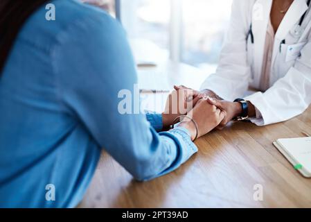 Mettre le cœur dans les soins de santé. un médecin tenant les mains d'un patient dans sa salle de consultation Banque D'Images