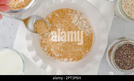 Femme préparant le petit déjeuner. Flocons d'avoine à base d'avoine entière, de farine de lin, de graines de Chia et de lait. Vue rapprochée du dessus Banque D'Images
