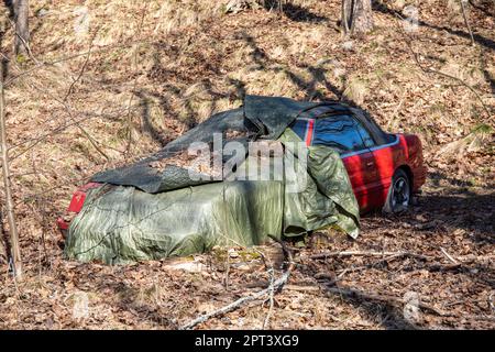 Berline décapotable rouge abandonnée recouverte d'une bâche verte dans le district de Vähä-Meilahti à Helsinki, en Finlande Banque D'Images