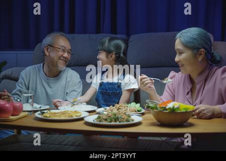 Happy Asian famille grand-parents et petite-fille dîner sur table et s'amuser pendant la maison soir, parent senior et enfant de bonheur manger Banque D'Images