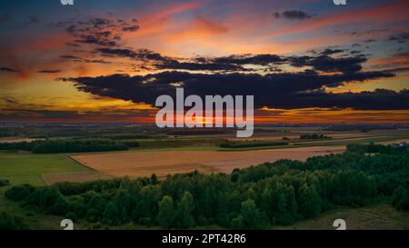 Coucher de soleil coloré au-dessus de la forêt et des champs aériens avec le soleil et les stations éoliennes lointaines, Podlaskie Voivodeship, Pologne, Europe Banque D'Images