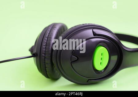 Casque noir se trouve sur un fond vert pastel colorés. Concept d'écoute musicale Banque D'Images