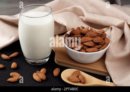 Un verre de lait d'amande sur la table, des amandes dispersées tout autour. Lait de remplacement à base d'amandes sans lactose. Banque D'Images